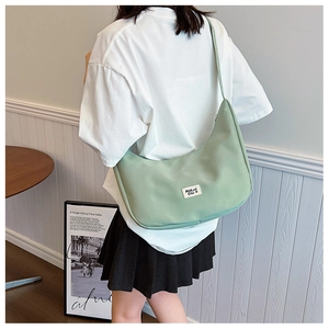 Detail of light green hobo saddle bag featuring a woven brand label and nylon texture