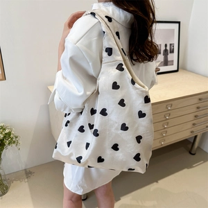 Sac fourre-tout tricoté blanc à motifs cœurs noirs porté par un mannequin chic