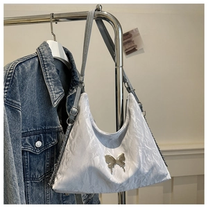 Détail du sac à bandoulière plissé argenté avec papillon métallique et chaîne