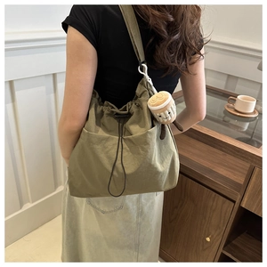 Detail of army green bucket bag featuring drawstring closure and cute plush charm