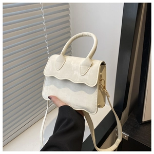 Detail of cream white crossbody bag featuring unique wavy edge flap and round handle