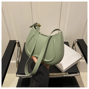 Detail of light green crescent underarm bag with smooth leather and gold metal hardware