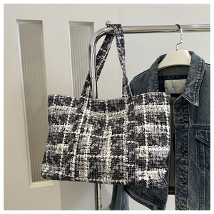 Detail of a large black and white tweed tote bag with classic houndstooth pattern weave