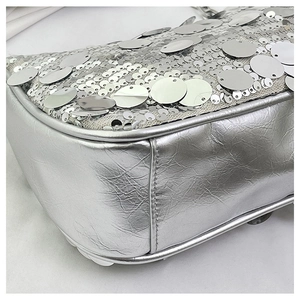 Close-up of silver sequins and metallic pleated leather texture on the shoulder bag