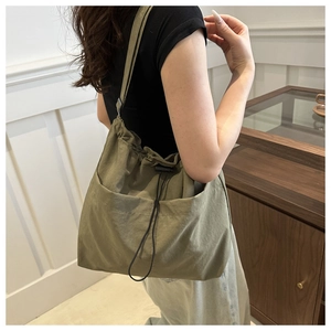 Close-up of olive green nylon bucket bag with drawstring closure and large front pocket