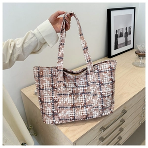 Detail view of a large plaid tote bag with textured tweed fabric and double handles