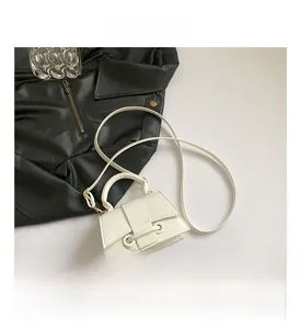 Detail view of a white minimalist leather handbag with buckle strap and thin shoulder strap