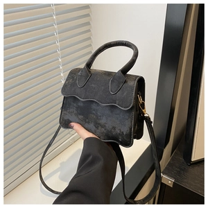 Detail showing vintage black textured handbag with wavy flap edge and circular top handle