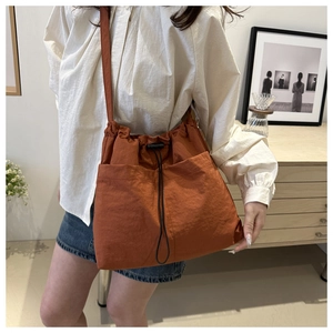 Dettaglio della borsa a secchiello in nylon arancione con chiusura a coulisse e tasche