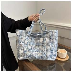 Detail of blue and white tweed tote bag showing woven texture and sturdy handle