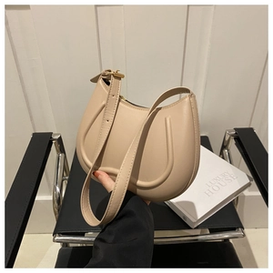 Detail of beige half-moon bag featuring U-shaped embossed lines and matte leather