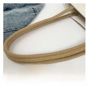 Gros plan de la bandoulière en coton tressé beige avec coutures renforcées sur le sac