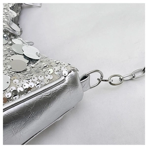 Detailed close-up of sparkling silver sequins and metal chain strap on a trendy women bag