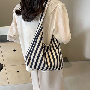 Minimalist navy blue striped canvas tote bag shown on model in a cozy indoor setting