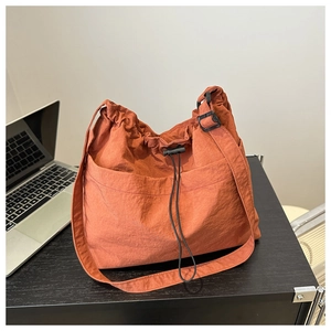 Macro shot of brick red nylon bucket bag showing drawstring closure and side buckle detail