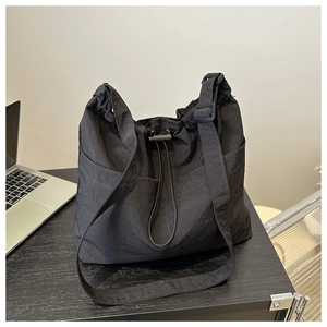 Close-up of black nylon bucket bag with drawstring closure and adjustable wide strap
