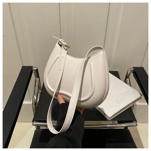Detail of a minimalist cream hobo bag with U-shaped embossing and gold hardware strap