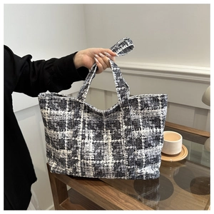 Detail of classic black and white tweed woven tote bag showing texture and handle