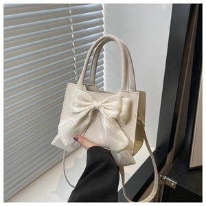 Détail d'un sac bandoulière blanc cassé avec grand nœud en organza et poignée
