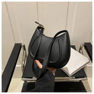 Detail of minimalist black crescent bag showing smooth leather texture and gold buckle
