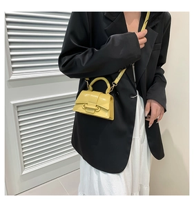 Close-up of a bright yellow mini leather square handbag with handle and crossbody strap