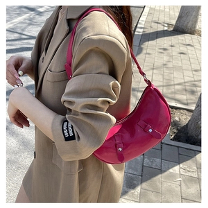 Detail shot of the rose red crescent bag showing dual silver buckles and glossy leather