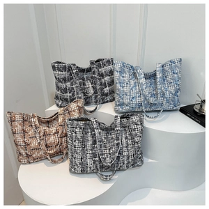 Detail view of woven tweed tote bags in four plaid patterns displayed on a white stand