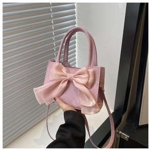 Détail du sac à bandoulière rose avec un grand nœud décoratif en texture de soie