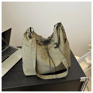 Detail of army green nylon bucket bag with drawstring closure and adjustable strap