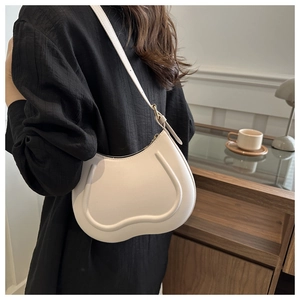 Minimalist beige crescent saddle bag with sleek piping detail on a striped shirt