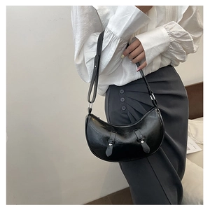 Detail of a black hobo crescent bag with wide straps and metallic decorative buckles