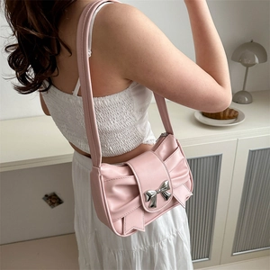 Pink French pleat underarm bag with large bow and metallic buckle in home setting