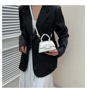 Detail of white glossy mini square bag with dual ring buckle on a black suit model
