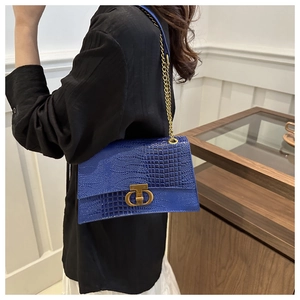 Dettaglio borsa blu motivo coccodrillo con fibbia CD in metallo dorato e tracolla