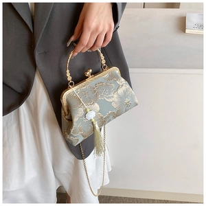 Detail einer Vintage-Stickerei-Handtasche mit goldenem Griff und Quastenanhänger