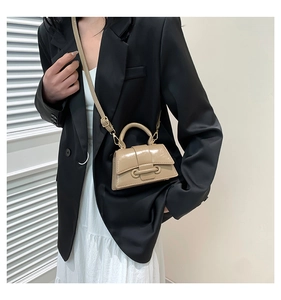 Mini khaki patent leather handbag styled with a black blazer and white dress on model