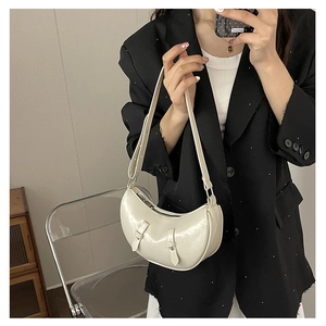 Mirror selfie showing a cream saddle shoulder bag with leather texture and buckle detail