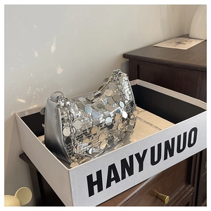 Detail of silver oversized sequins on a trendy shoulder bag with metallic chain strap