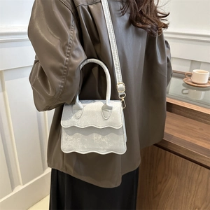 Minimalist light blue square bag with wavy flap and cracked texture shown on model crossbody