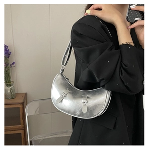 Detail of silver metallic crescent bag with pleated texture and stylish belt buckles