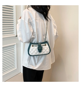 Quilted diamond chain bag with green trim shown on model against minimalist white background