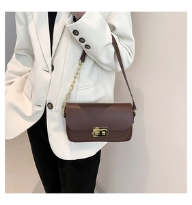 Detail of vintage brown leather handbag with gold twist lock and metal chain strap