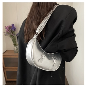 Silver crescent underarm bag shown on model wearing black blazer in lifestyle setting