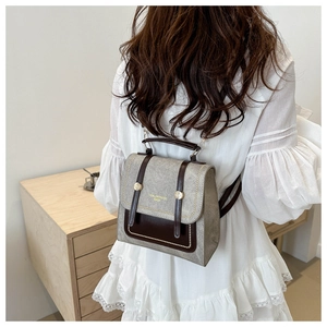 Detail of college style backpack with grey textured fabric and brown leather flap