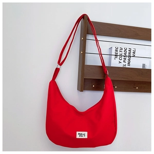 Close-up of a red waterproof nylon crescent bag with adjustable strap and logo detail
