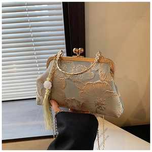 Close-up of luxury silk shell handbag featuring elegant floral embroidery and metallic frame