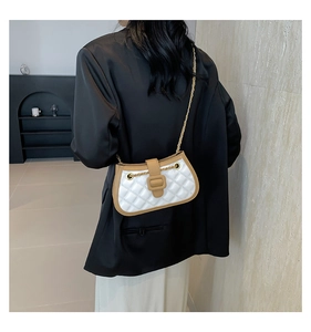 Detail of white quilted rhombic texture and brown leather trim on a chain bag