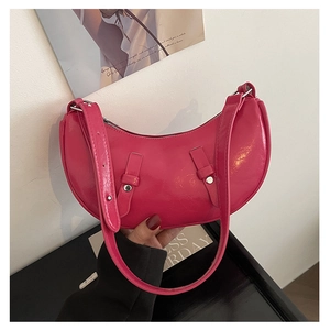 Close-up of bright pink crescent bag with glossy patent leather finish and silver studs