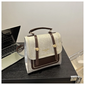 Detail of vintage canvas crossbody bag with brown leather trim next to a laptop