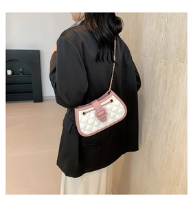 Quilted crossbody bag shown on shoulder, pink and white design with metal chain strap